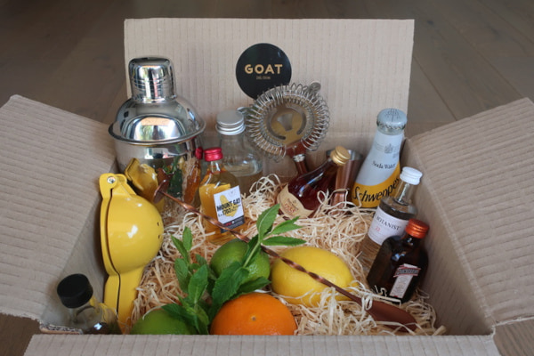 Cardboard box filled with cocktail making ingredients and tools