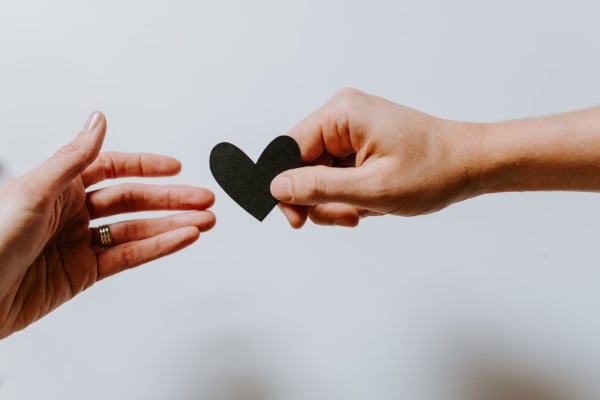 Hands passing a paper heart to eachother