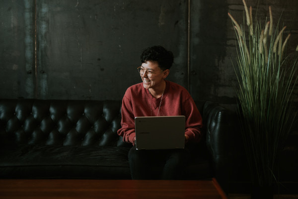 Person laughing while sat on sofa with laptop on their lap