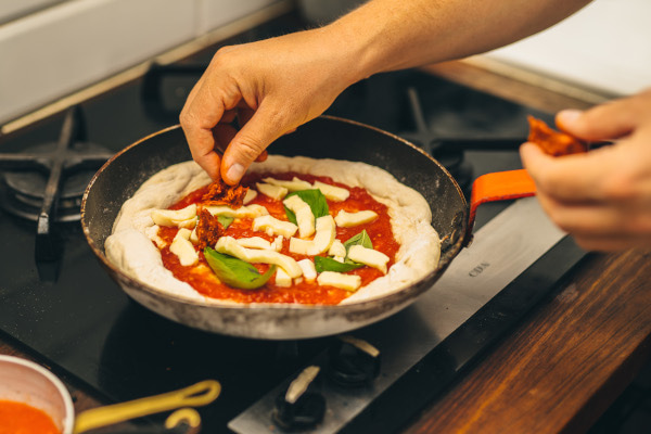 Someone making pizza in a frying pan