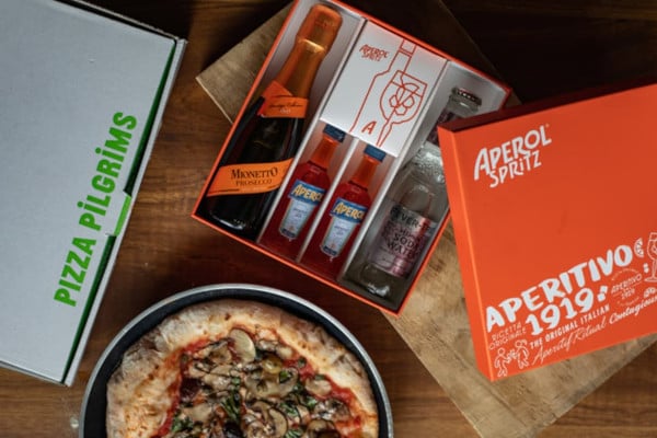 Pizza in a frying pan and spritz kit in an orange box