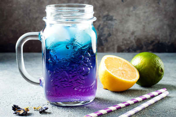 Colourful lemonade in a glass jar with paper straws