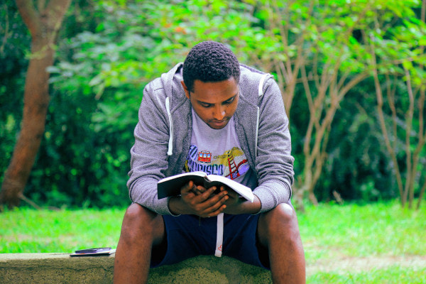 Man reading outside on a log