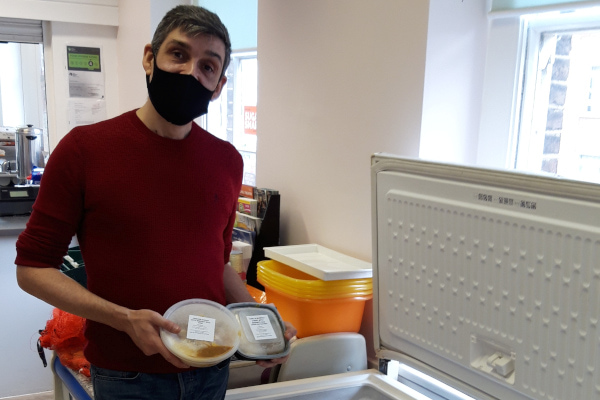 Clockhouse volunteer in a mask holding up donated food