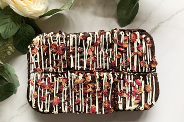 Brownie block decorated with white icing and pink petals