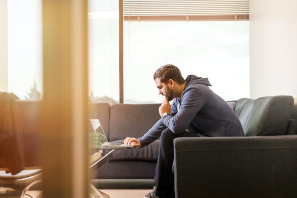 man sitting on sofa looking at laptop