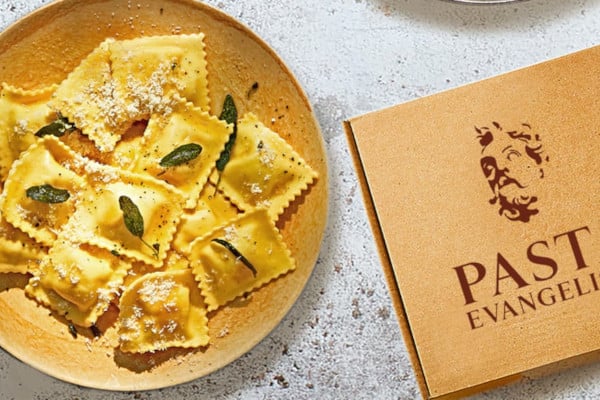 bowl of pasta next to Pasta Evangelists cardboard box