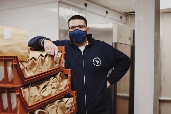 Whitechapel Mission volunteer standing next to food donations